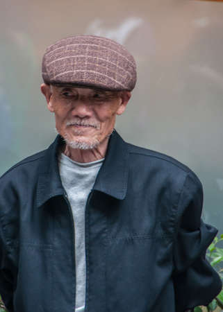 Shanghai, China - May 4, 2010: Portrait closeup of older senior man with big brown had on. Gray turtle neck shirt and marine-blue vest.のeditorial素材