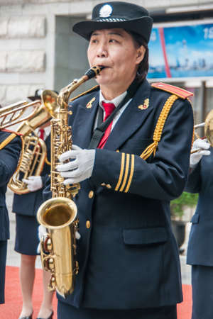 Shanghai, China - May 4, 2010: Closeup of woman in marine-blue and gold, member of all female marching band, blowing her saxophone.のeditorial素材