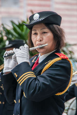 Shanghai, China - May 4, 2010: Closeup of woman in marine-blue and gold, member of all female marching band, blowing her flute.のeditorial素材