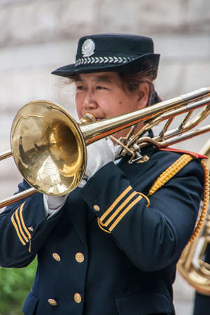 Shanghai, China - May 4, 2010: Closeup of woman in marine-blue and gold, member of all female marching band, blowing her trombone.のeditorial素材