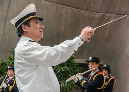 Shanghai, China - May 4, 2010: Closeup of male conductor in white and gold, directing all female marching band.のeditorial素材