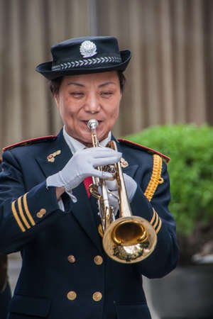 Shanghai, China - May 4, 2010: Closeup of woman in marine-blue and gold, member of all female marching band, blowing her trumpet.のeditorial素材