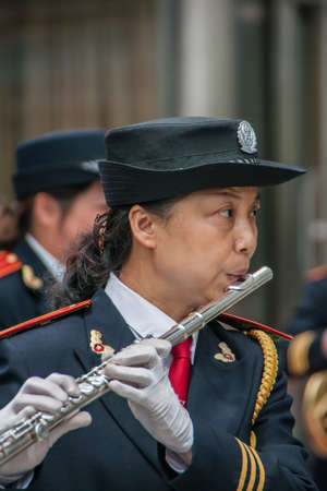 Shanghai, China - May 4, 2010: Closeup of woman in marine-blue and gold, member of all female marching band, blowing her modern long flute.のeditorial素材