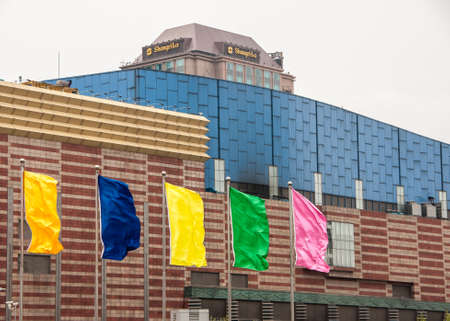 Shanghai, China - May 4, 2010: Pudong, Lujiazui district. Shangri-la hotel peeks over blue and brown-beige wall with several flags of different colors in front.のeditorial素材