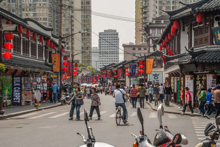 Shanghai, China - May 4, 2010: Yuyuan shopping streets. Wider street leading to center, with Chinese traditional architecture buildings and red lanterns on both sides . Plenty of people.のeditorial素材