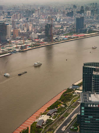 Shanghai, Pudong, Lujiazui, China - May 4, 2010: Sea of highrise buildings on other side of Huangpu River as seen from Oriental Pearl TV Tower. Boats on brown water. Smog on horizon.のeditorial素材