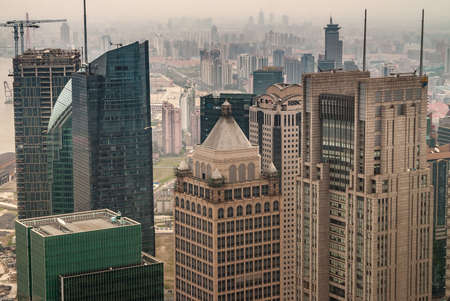 Shanghai, Pudong, Lujiazui, China - May 4, 2010: HSBC building partly hidden among other brown stone and green glass skyscrapers with smog over other highrises on horizon.のeditorial素材