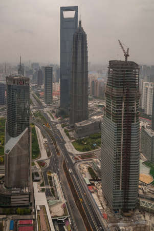 Shanghai, Pudong, Lujiazui, China - May 4, 2010: Tower under construction with Jinmao and World Financial Center in back. Bank of China skyscraper on side. Wide road. Smog covers horizon.のeditorial素材