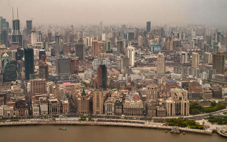 Shanghai, China - May 4, 2010: Aerial view on historic section of The Bund behind brown Huangpu River and sea of highrise buildings under smog as backdrop. Huangpu Park on right bottom.のeditorial素材