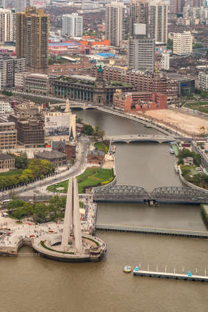 Shanghai, China - May 4, 2010: Aerial portrait on gray Wusong river emptying in brown Huangpu River at green park and Waibaidu bridge with highrise buildings as backdrop.のeditorial素材