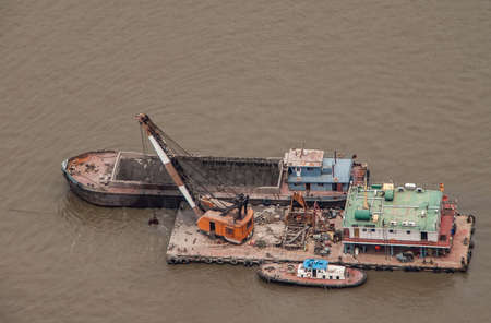 Shanghai, China - May 4, 2010: Aerial closeup on dredging operation with barge and orange crane on brown Huangpu River.のeditorial素材