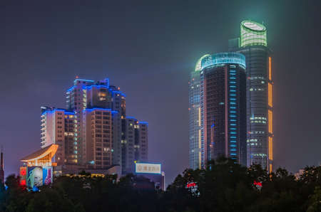 Shanghai, Xuhui, China - May 3, 2010: Night photo. Colorfully lighted skyscrapers peep over dark trees of Xujiahui Park.のeditorial素材