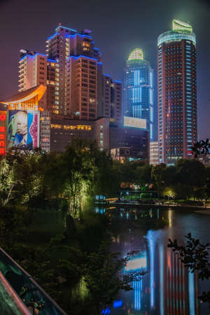 Shanghai, Xuhui, China - May 3, 2010: Night portrait. Colorfully lighted skyscrapers peep over dark trees of Xujiahui Park.のeditorial素材