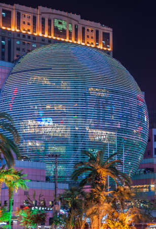 Shanghai, Xuhui, China - May 3, 2010: Night photo of colorfully lighted half globe covering multi-levels of facade of shopping mall with palm trees up front.のeditorial素材