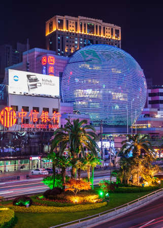 Shanghai, Xuhui, China - May 3, 2010: Night portrait photo of colorfully lighted half globe covering multi-levels of facade of shopping mall and highrise buildings with palm trees up front.のeditorial素材