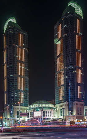 Shanghai, Xuhui, China - May 3, 2010: Night closeup of Grand Gateway twin towers and mall, all colorfully lighted. Car light draw lines on road.のeditorial素材