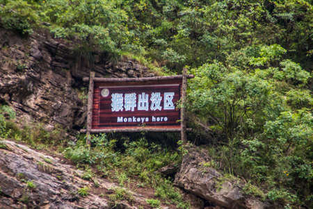 Wuchan, China - May 7, 2010: Dawu or Misty Gorge on Daning River. light blue on brown warning sign for Rhesus monkeys, set on brown rocky slope against green foliage backdrop.のeditorial素材