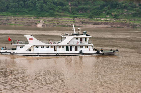 Fengdu, Chongqing, China - May 8, 2010: Yangtze River. Closeup of white river police patrol speed boat on brown water with green shoreline in back.のeditorial素材
