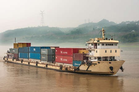 Chongqing, China - May 8, 2010: Yangtze River. Closeup of Yellow shipping container boat sailing on...
