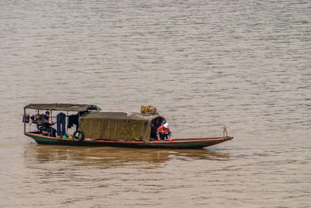 Myaoyinan Chongqing, China - May 8, 2010: Yangtze River. Closeup of sloop with dirty brown cabin and 2 men, 1 wearing red shirt, preparing to fish in brown water.のeditorial素材