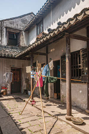 Tongli, JIangsu, China - May 3, 2010: Hutong network of narrow walkways, simple housing, and small businesses. View on courtyard of house with drying laundry adding color.のeditorial素材