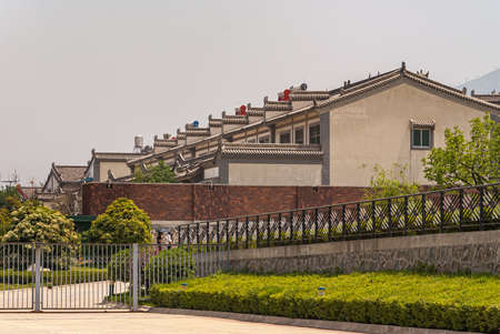 Xian, China - May 1, 2010: Better brown stone housing in gated community with green foliage under silver sky.のeditorial素材