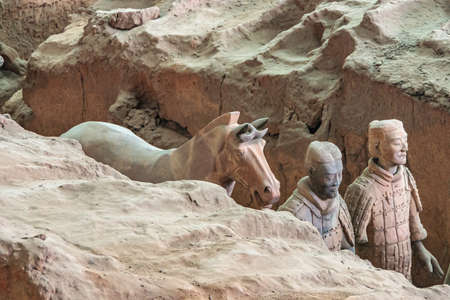 Xian, China - May 1, 2010: Terracotta Army museum and hall. Horse and 2 gray-beige ancient soldier sculptures at excavation.のeditorial素材