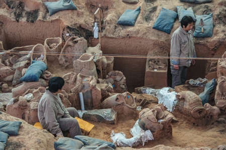 Xian, China - May 1, 2010: Terracotta Army museum and hall.  2 researchers working in the dirt,...
