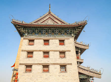 Xian, China - April 30, 2010: North Gate of Huancheng City Wall. Side facade in Chinese traditional architecture of palace on top of gate against blue sky. Beige stone wall, wooden decorated roof and window blinds.のeditorial素材