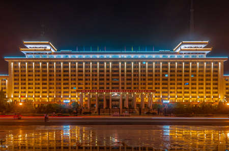 Xian, China - May 1, 2010: Black night landscape closeup. Lighted up Shaanxi Peoples Government Office Building. Reflection in wet surface.のeditorial素材