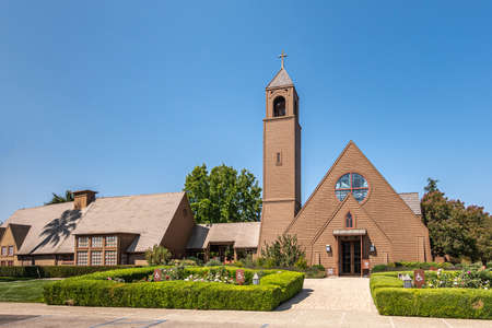 Los Olivos, California, USA - September 3, 2020: Frontal viw on brown wood St. Marks in the Valley Church with bell tower set in green park under blue sky, including side buildings.のeditorial素材