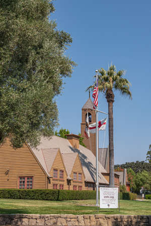 Los Olivos, California, USA - September 3, 2020: Portrait of brown wood St. Marks in the Valley Church with bell tower set in green park under blue sky, including side buildings. Flag post and info poster.のeditorial素材