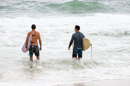 Surfers heading out to catch a waveの写真素材
