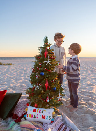 Two brothers admiring a christmas tree on the beach at sunsetの写真素材