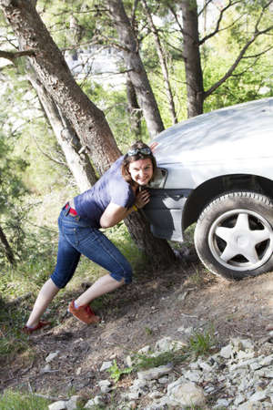 Girl pushes car after accident on wood roadの写真素材