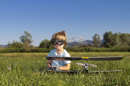 Cute young boy and his RC plane, sitting on grassの写真素材