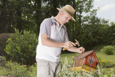 Man using a hammer to nail together old bird house-の写真素材