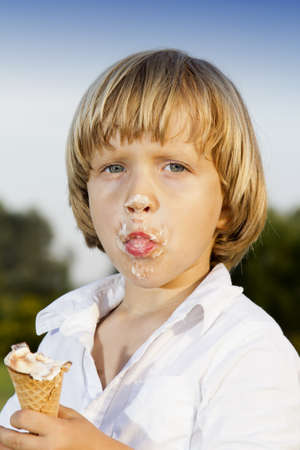 Young cute boy eating a tasty ice cream, outdoors on sunny summer afternoonの写真素材