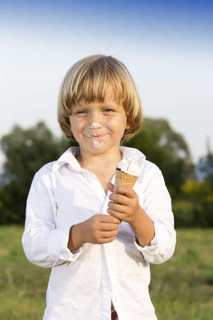 Young cute boy eating a tasty ice cream, outdoors on sunny summer afternoonの写真素材