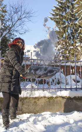 Cute middle aged woman shoveling and removing snow in front of her house in the cityの写真素材