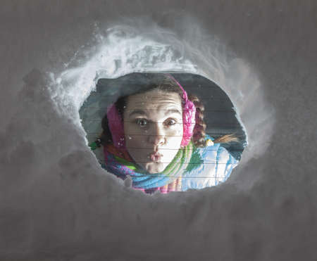 Young  woman driver surprised  looking  from behind a snowy car window 