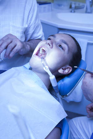 Cute girl having her teeth checked by doctor-- medical blue colorized