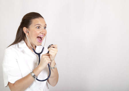 Attractive young female doctor singing to her stethoscope, space for textの写真素材