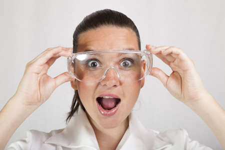 Woman closeup portrait of young doctor, surgeon or nurse, looking surprised starring with big eyes wearing protective glassesの写真素材