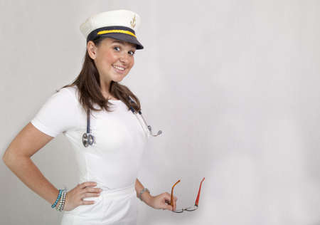 Cute smiling female doctor in captain cap, leader of medical crew on big luxury cruiser の写真素材