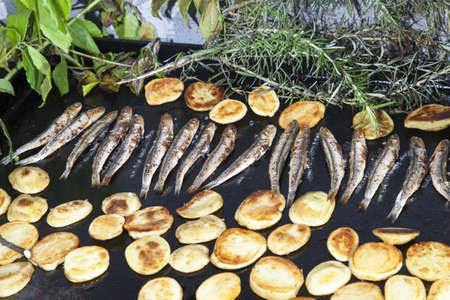 Fresh Mediterranean sardines, mackerel fishes and sliced organic potatoes, grilled and smoked with vine leaves, laurel, rosemary and fennel, selective focusの写真素材