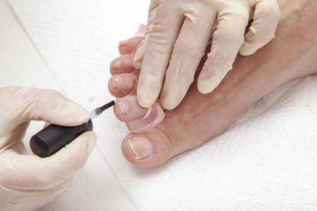 Close up of a beautician preparing and applying a nail polish  to a client feetの写真素材