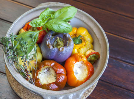 Baked spicy colorful peppers stuffed with goat and lamb cheese, garnished with basil, thyme, parsley, close up, selective focusの写真素材