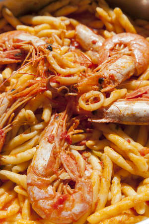 Delicius hand made pasta with scampi, calamari, seafood, organic tomato sauce and Mediterranean herbs, close upの写真素材
