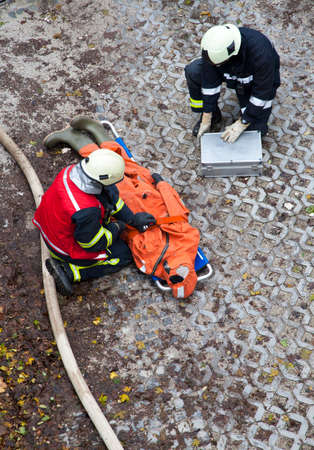 The rescue workers strapping hurt person  dummy  on a stretcher, during  a training exercise のeditorial素材
